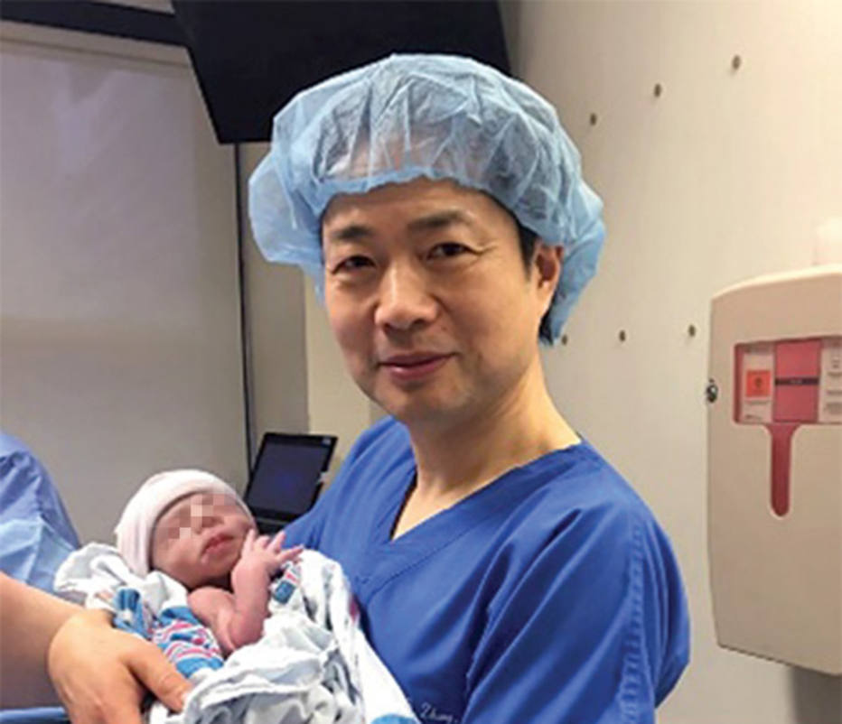 John Zhang sostiene al bebé en el momento de su nacimiento. / New Scientist