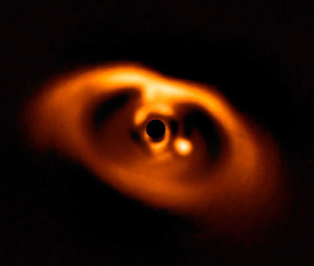 Primera imagen de la formación del planeta PDS 70b, visible como un punto brillante a la derecha del centro de la imagen y que queda oscurecido por la máscara del coronógrafo, que bloquea la intensa luz de la estrella central- ESO, A. Müller et al.