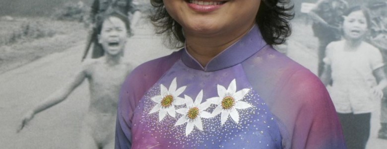 Kim Phuc junto a la fotografía de la niña del napalm