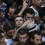 Un refugiado sirio aprieta los ojos enmedio de un grupo de personas que busban registrarse en el estadio nacional de la isla griega de Kos, 12 de agosto de 2015- REUTERS, Alkis Konstantinidis
