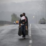 Un refugiado sirio besa a su hija mientras camina bajo una tormenta hacia la frontera de Grecia con Macedonia, cerca de la localidad griega de Idomeni, 10 de septiembre de 2015- REUTERS, Yannis Behrakis