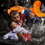 Un refugiado sirio se aferra a sus hijos mientras lucha para bajar de un bote en la isla griega de Lesbos, 24 de septiembre de 2015- REUTERS / Yannis Behrakis