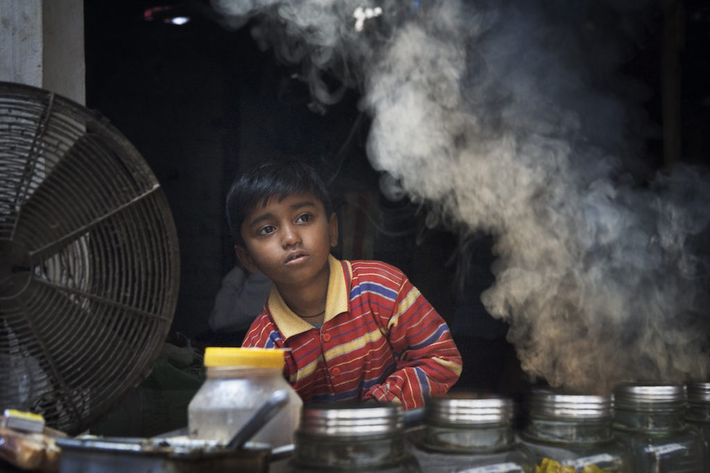 Niño vendedor callejero , con humo, en Varanasi Benares India
